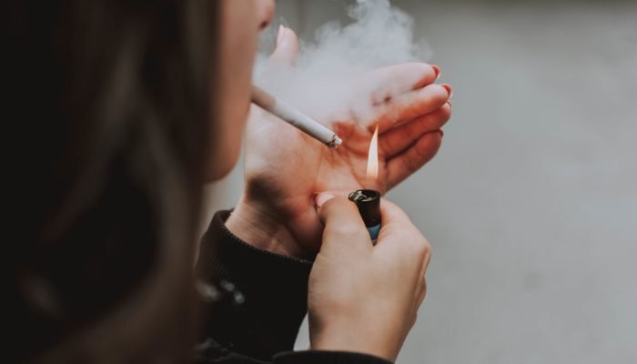 A selective closeup shot of a female lighting up a cigarette with a lighter
